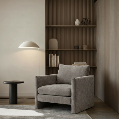 Gray armchair in a modern room with a bookshelf and floor lamp.